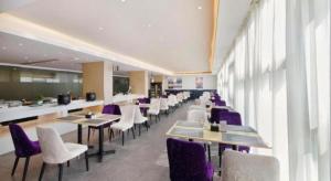 a restaurant with tables and chairs and purple chairs at Lavande Hotels Xinyu Chengbei Square in Xinyu