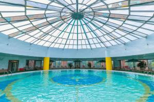 une grande piscine avec un plafond voûté dans l'établissement Grand Metropark Hotel Nanjing, à Nankin