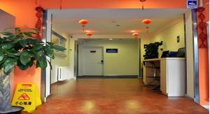 un couloir de bureau avec une porte ouverte et une usine dans l'établissement 7 Days Inn Beijing Zhongguancun Suzhouqiao, à Pékin