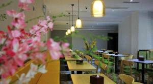 un restaurant avec des tables et des chaises et des fleurs roses dans l'établissement Vatica Fuzhou West Second Ring Road Xihu Park Hotel, à Fuzhou
