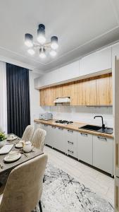 eine Küche mit einem Tisch und Stühlen sowie eine Küche mit weißen Schränken in der Unterkunft Жк Керуен Сарай in Türkistan