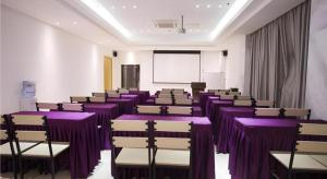 une chambre avec des tables et des chaises violettes et un écran dans l'établissement City Comfort Inn Zhanjiang Shimao Building Chikan Old Street, à Tchia-k'am