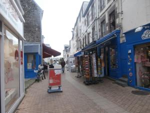 a city street with blue stores and a sign on the sidewalk at GAUTIER 3 Etoiles in Granville