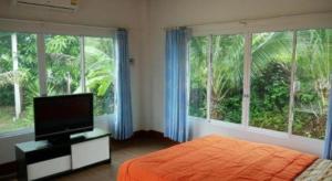 Un dormitorio con una cama y un televisor y ventanas. en OYO 1036 Ban Bum Resort, en Ban Pa Khan