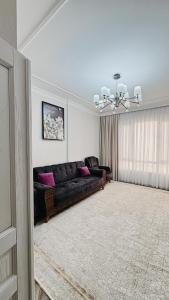 ein Wohnzimmer mit einem schwarzen Sofa und rosa Kissen in der Unterkunft Жк Керуен Сарай in Türkistan