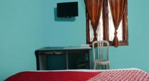 a desk in a blue room with a table and a chair at Hotel O Penginapan Raja in Citepus