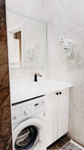 ein weißes Badezimmer mit Waschmaschine und Spiegel in der Unterkunft Жк Керуен Сарай in Türkistan + 11 Fotos