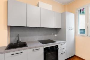 une cuisine avec des armoires blanches et un évier dans l'établissement Casa Iris 2, à Poggio