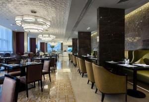 une salle à manger avec des tables et des chaises dans un restaurant dans l'établissement Jiuhua Jin Jiang International Hotel, à Zhenjiang