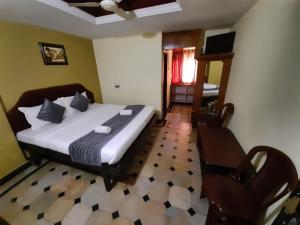 a bedroom with a bed and a chair in it at Hotel caveri comfort in Madikeri +16 photos