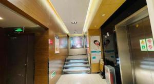 un couloir avec des escaliers dans un immeuble avec des affiches dans l'établissement Jinjiang Inn Tai'an Taishan Railway Station, à Tai'an