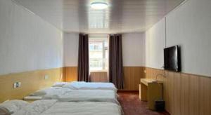 ein Schlafzimmer mit zwei Einzelbetten und einem Fernseher in der Unterkunft 7 Days Inn Tianjin Zhongshan Road North Station in Tianjin