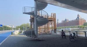 eine Wendeltreppe neben einer Brücke mit einem Mann und einem Fahrrad in der Unterkunft IU Hotel Tianjin Fumin Qiao Branch in Tianjin