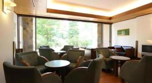 une salle d'attente avec des tables et des chaises et une grande fenêtre dans l'établissement Hotel Harvest Tateshina, à Tateshina