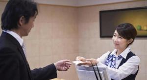 a woman is handing a man a piece of paper at Hotel Sealuck Pal Yaizu in Hanazawa