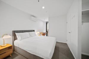 ein Schlafzimmer mit einem großen weißen Bett und einem Tisch in der Unterkunft Sleek 2-Bed Apartment with Rooftop Garden Access in Belconnen