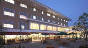 un grand bâtiment avec des tables et des parasols devant lui dans l'établissement Hotel Ligare Kasugano, à Nara