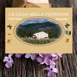 a picture of a white house in a field with purple flowers at La Casa nella Vecchia Ferrovia in Arsiero