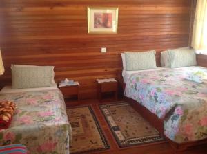 two beds in a room with wooden walls at Bwigamiro Country Home Fort Portal in Fort Portal