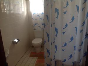 łazienka z toaletą i zasłoną prysznicową z niebieskimi delfinami w obiekcie Bwigamiro Country Home Fort Portal w mieście Fort Portal