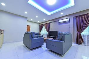 un salon avec deux chaises bleues et une télévision dans l'établissement OYO 90522 Alma Sweet Home, à Juru