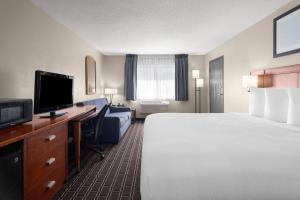 ein Hotelzimmer mit einem Bett und einem Flachbildfernseher in der Unterkunft Travelodge by Wyndham Fargo in Fargo
