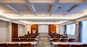 ein Konferenzraum mit Tischen und Stühlen und einer Leinwand in der Unterkunft Metropolo Hotel Suzhou Guogou Plaza Huaxia in Suzhou