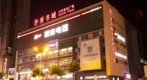 un bâtiment avec des enseignes au néon dans une ville la nuit dans l'établissement Borrman Hotel Zhenjiang Dashikou Suning Plaza, à Zhenjiang
