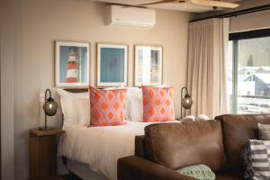 ein Schlafzimmer mit einem Bett und einer Couch und einem Fenster in der Unterkunft Oceanfront Duplex Apartments, Hermanus Waterfront in Hermanus