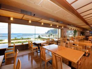 a restaurant with tables and chairs and a view of the ocean at Atami Seaside Spa & Resort in Atami