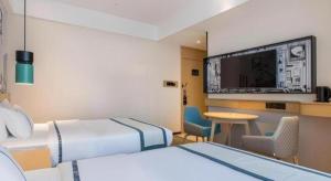 ein Hotelzimmer mit zwei Betten und einem Flachbildfernseher in der Unterkunft City Comfort Inn Ji'an South Administrative Center in Ji'an