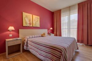 a bedroom with a bed and a red wall at Apartamentos Mar Comillas in Comillas