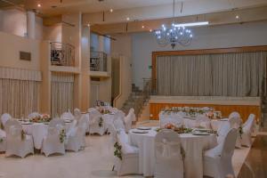 Un salón de banquetes con mesas y sillas blancas. en Riebeek Valley Hotel, en Riebeek-Wes