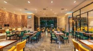 a restaurant with wooden tables and green chairs at Zmax Hotel Guangzhou Railway Station in Guangzhou