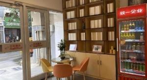 a restaurant with a drink cooler and a table and chairs at Shell Hotel Yinchuan Xingqing District Yuhuangge Street in Yinchuan