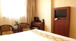 a hotel room with a bed and a desk and a television at GreenTree Inn Cangzhou Construction Avenue Express in Cangzhou