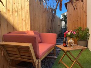 een bank en een tafel met een fles wijn bij Caprice Gruissanais Suite avec Spa privatif in Gruissan