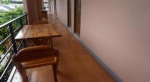 une rangée de tables et de chaises en bois sur un balcon dans l'établissement Bumnsaya Place, à Ban Nong Samet