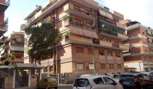 wysoki budynek z zaparkowanymi przed nim samochodami w obiekcie Roma Tourist House w Rzymie