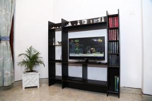 a black entertainment center with a television in a room at The Peppermint in Kandy