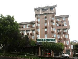 un grand bâtiment rose avec des arbres devant lui dans l'établissement GreenTree Inn Nanjing Gaochun District Old Street Scenic Spot Express Hotel, à Gaochun