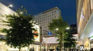 nachts eine Stadtstraße mit Gebäuden und Bäumen in der Unterkunft KEIKYU EX INN Keikyu Kawasaki-Station in Kawasaki