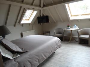 a bedroom with a bed and two windows and a table at B&B Castel 't Haantje in Ruiselede