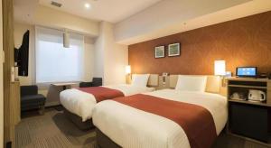 ein Hotelzimmer mit zwei Betten und einem Fernseher in der Unterkunft KEIKYU EX INN Keikyu Kawasaki-Station in Kawasaki + 197 Fotos