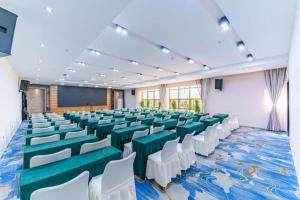 une salle de conférence avec des chaises vertes et blanches et un écran dans l'établissement Jinjiang Inn select Hotel Kunming Economic Development Zone Kunming College, à Kunming