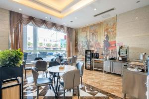 une salle à manger avec une table et des chaises et une cuisine dans l'établissement Vienna 3 Best Hotel Dongguan Liaobu Shida Road, à Liaobu