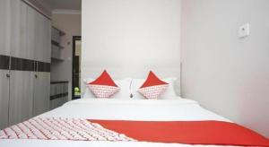 une chambre avec un lit blanc avec des oreillers rouges dans l'établissement Super OYO 270 Madinah Residence Syariah, à Talang Kelapa 49 autres photos
