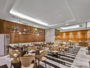 ein Restaurant mit Tischen und Stühlen in einem Raum in der Unterkunft Jinjiang Metropolo Nanchang Honggutan Wanda Plaza in Nanchang