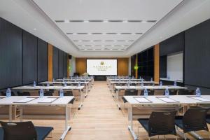 ein Raum mit Tischen und Stühlen und einer Projektionsleinwand in der Unterkunft Jinjiang Metropolo Nanchang Honggutan Wanda Plaza in Nanchang