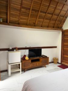 a bedroom with a tv on a wooden entertainment center at Villa Aiden Bungalow 3 near luwatu in Ungasan